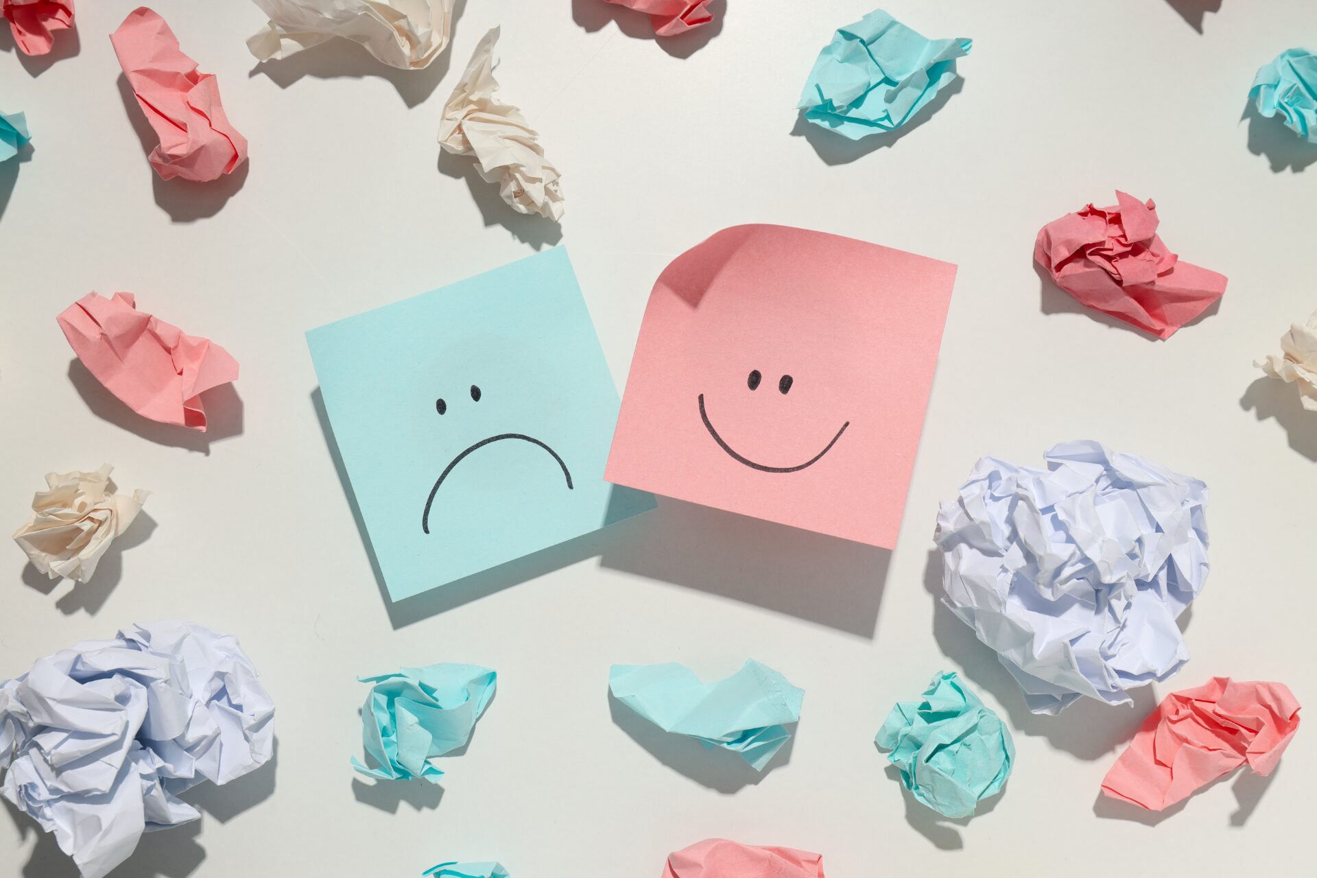 Sad and smiling faces on colorful notes, reflecting shifts in investor sentiment as market conditions change.